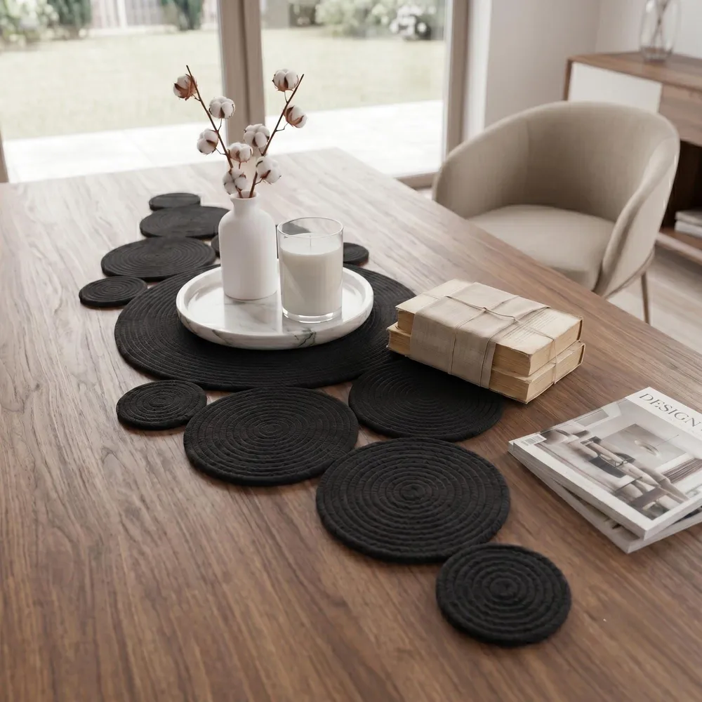 Black cotton rope dining table centerpiece styled with books, decorative tray, candle and vase on rustic wooden dining table