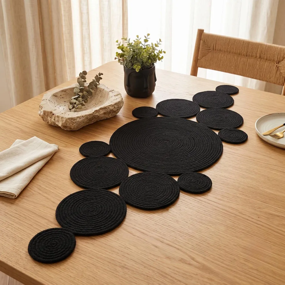 Handmade black cotton rope table centerpiece displayed on a light oak dining table with neutral Japandi decor, ceramic vase and natural daylight, modern minimalist home styling
