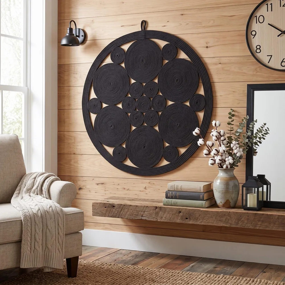 Black cotton rope wall art above a console beside a wall clock in a warm moody living room