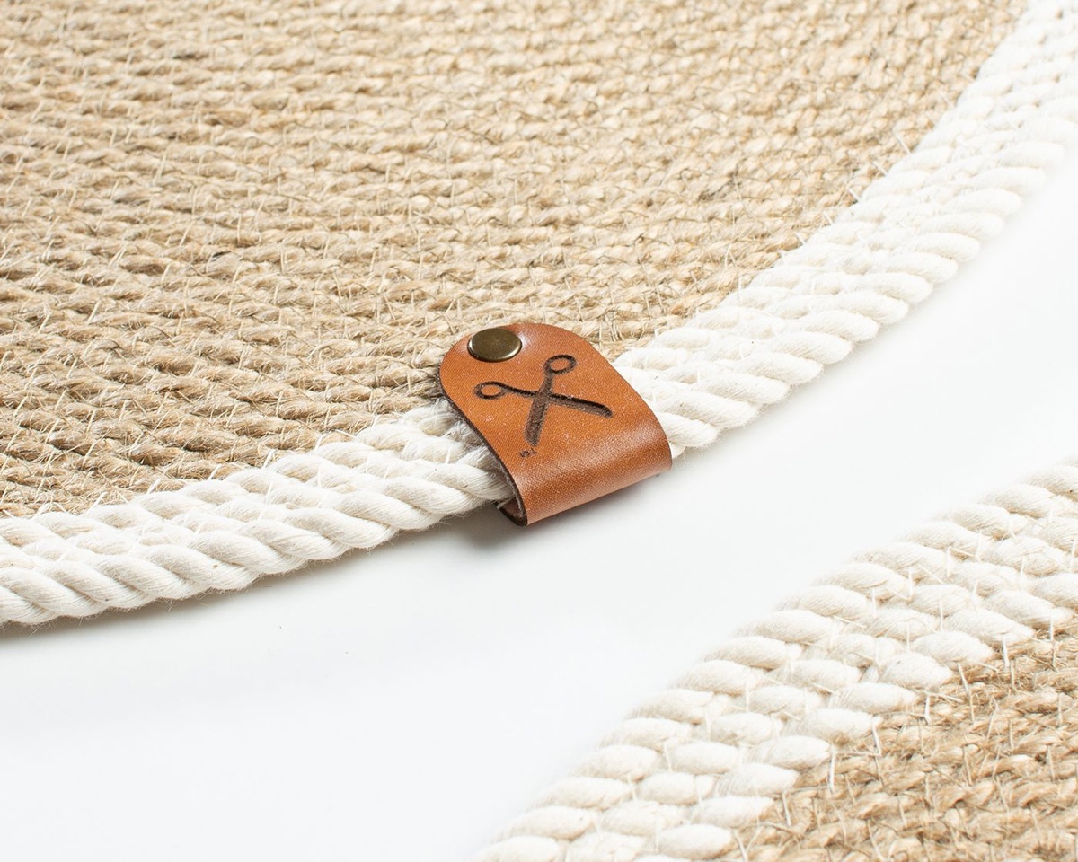 Close-up of the faux leather Homever tag with a brass rivet on the edge of a coiled jute piece
